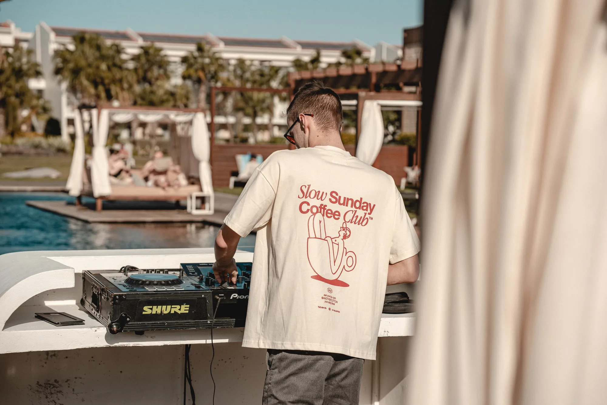 DJ Moritz legt am Pool auf den Kapverden auf, im Hintergrund Strandliegen