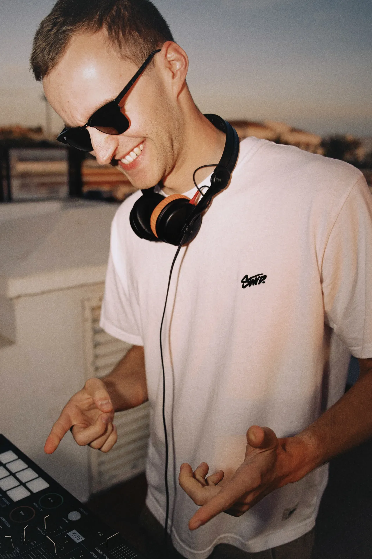 DJ Moritz mit Sonnenbrille und Kopfhörern lacht am DJ-Pult
