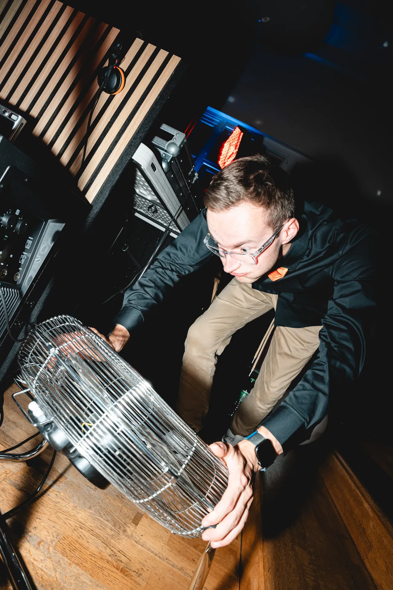 DJ Moritz trägt einen Retro-Ventilator über die Tanzfläche, hinter ihm das DJ-Pult