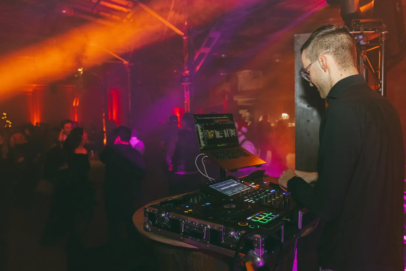 DJ Moritz am Pult bei einer Firmenfeier im orangen Licht