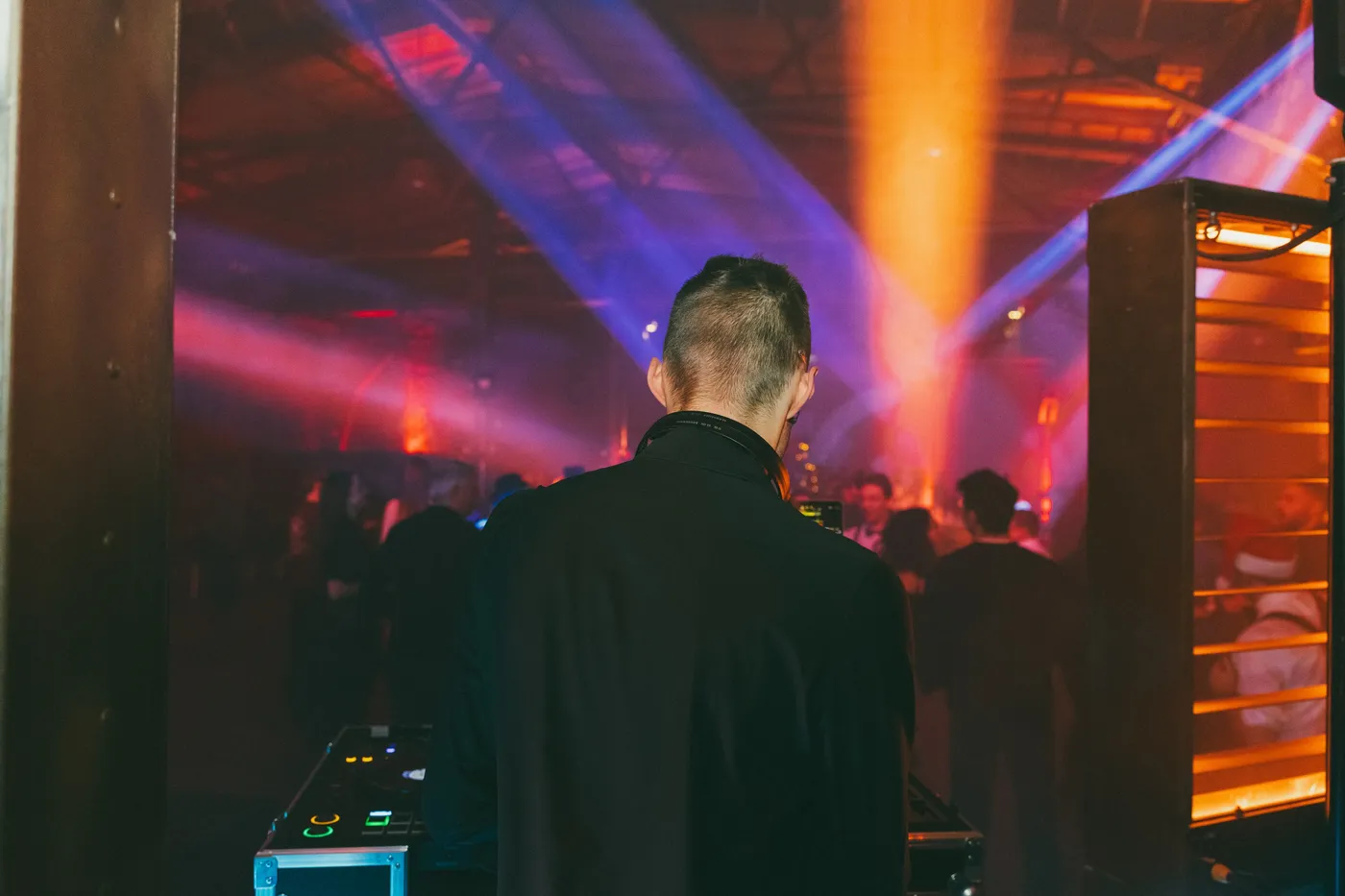 DJ Moritz von hinten am Pult, vor ihm tanzt das Publikum im bunten Licht