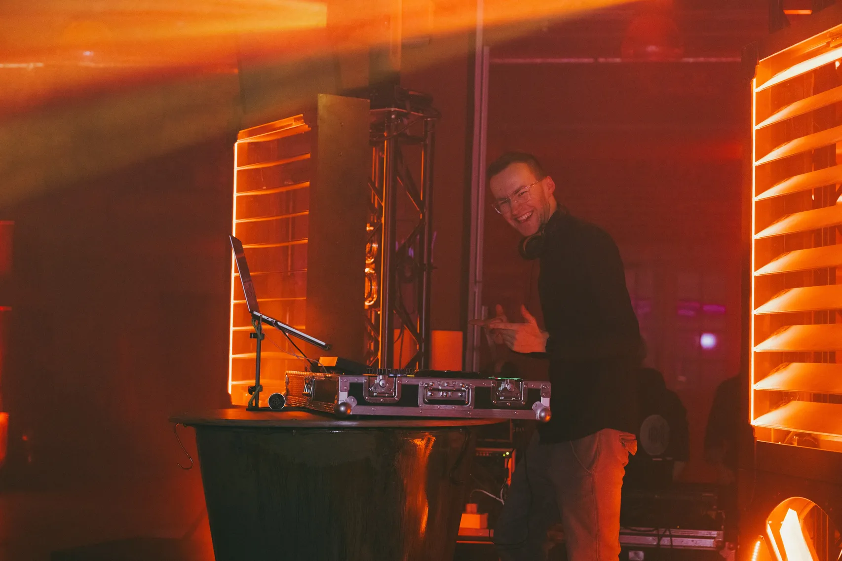 DJ Moritz am Pult bei einer Firmenfeier, hinter ihm leuchten orange Lichtsäulen
