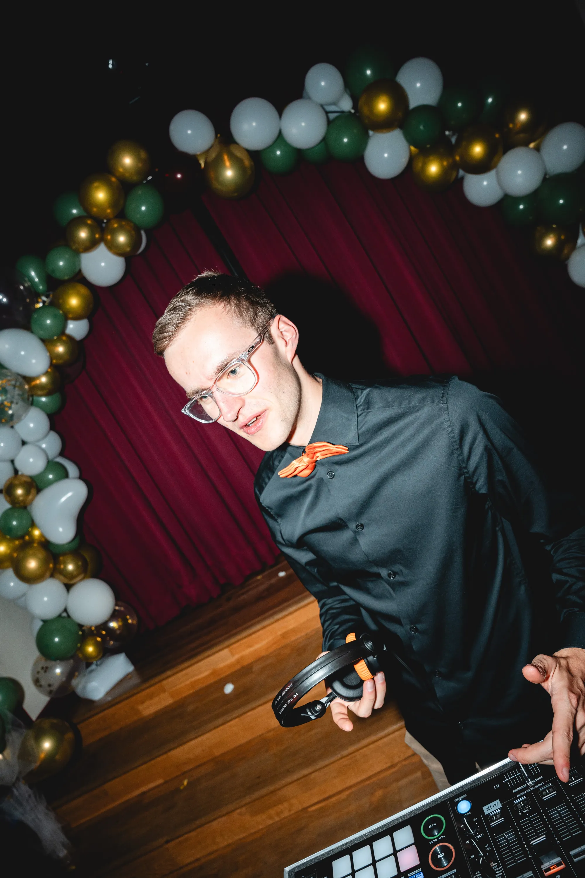DJ Moritz lacht am DJ-Pult vor einem Ballonbogen