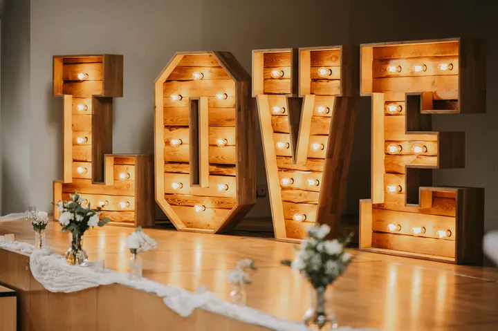 Leuchtende XXL LOVE-Buchstaben mit Glühbirnen vor einer Hochzeitstafel