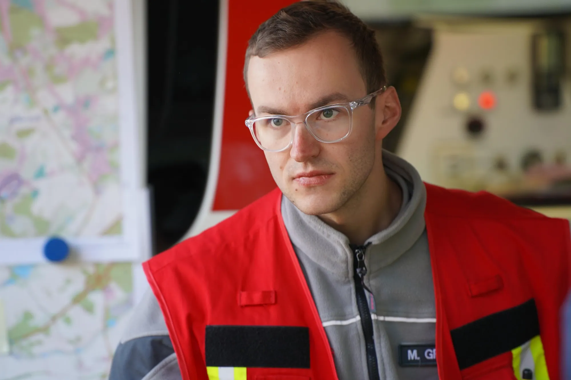 Moritz in roter Einsatzweste vor einer Lagekarte im Einsatzfahrzeug